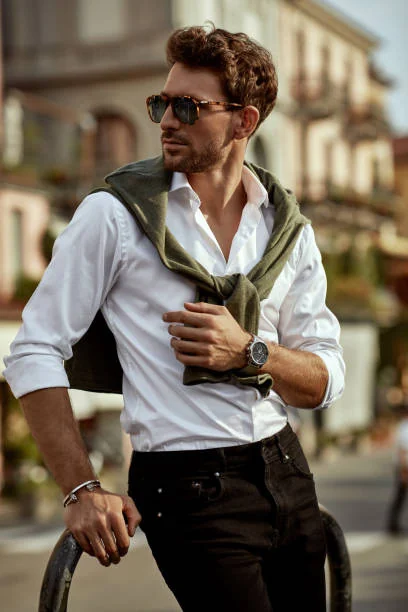Photo of a man in a white shirt with a green sweater tied over his shoulders